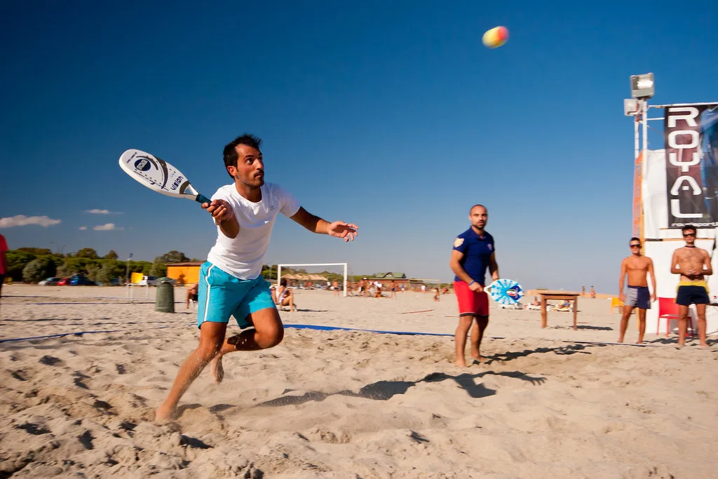 Jogador de beach tennis atacando a bola na areia