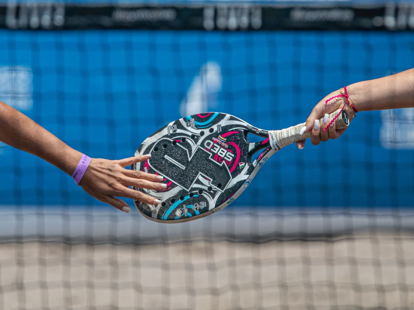 Raquete de beach tennis sendo passada sobre a rede